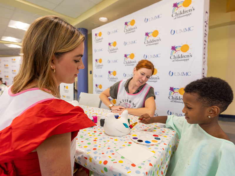 Children's of Mississippi patient Messiah Hamilton paints with PGA TOUR Wives Association member Kelsie Shelton. Jay Ferchaud/ UMMC Photography